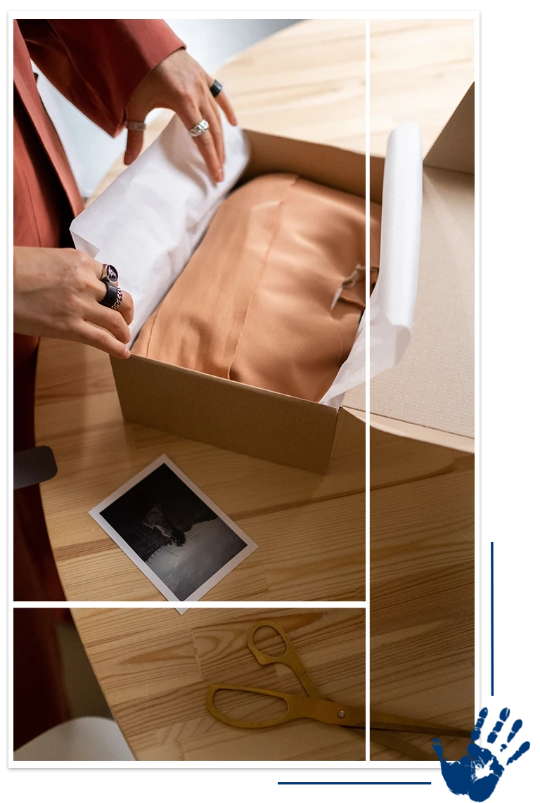 A person opening up an open box on top of a table.